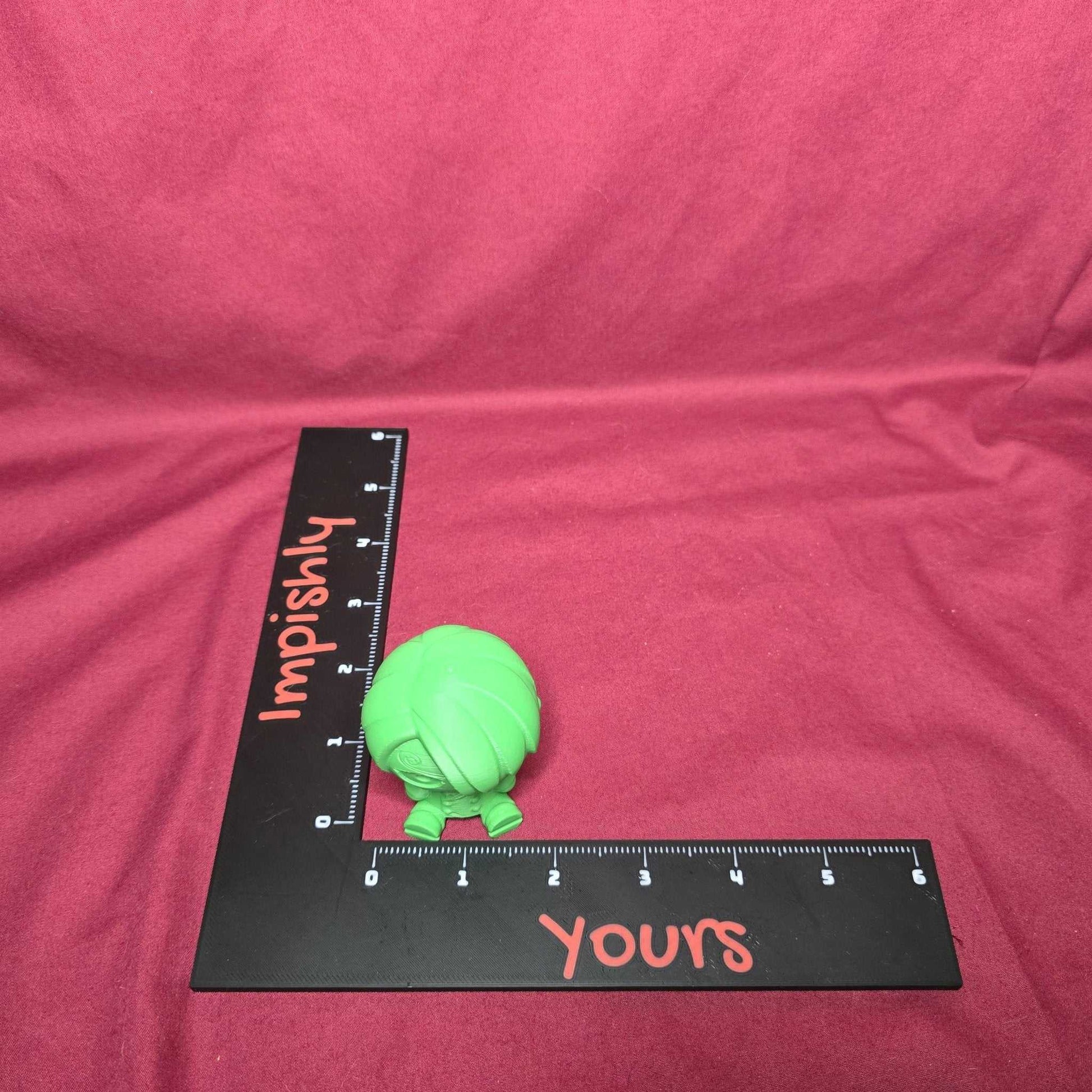 Top view of green Chibi Sanji Figure - 3D One Piece Collectible with ruler showing scale, placed on red background.
